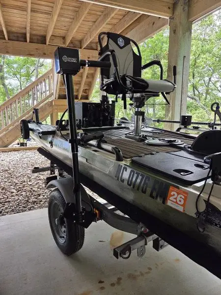 Kayak on trailer beneath wooden structure.